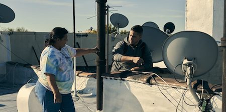 un homme et une femme sur le toit d'un immeuble parmi les antennes