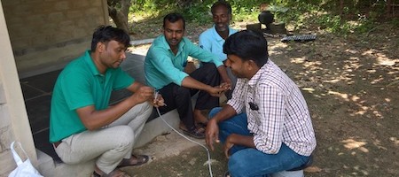 four men sitting on the ground and talking