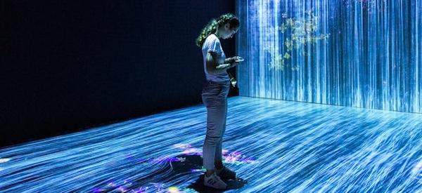 A woman standing in front of a large screen projected with water.