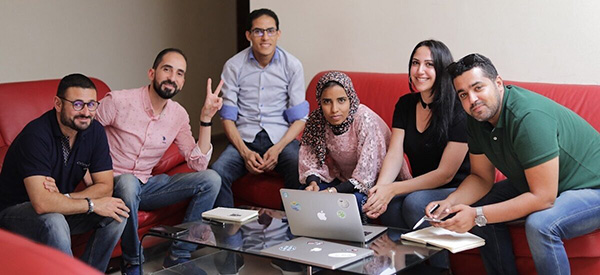 seis personas sentadas en el sofá con una computadora portátil frente a ellos en la mesa