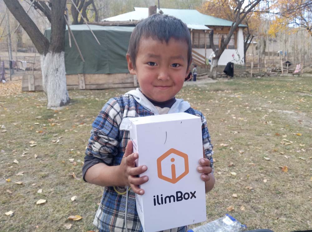 A kid holds a white box that reads: ilimBox