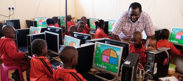 enfants assis dans une salle de classe devant les ordinateurs