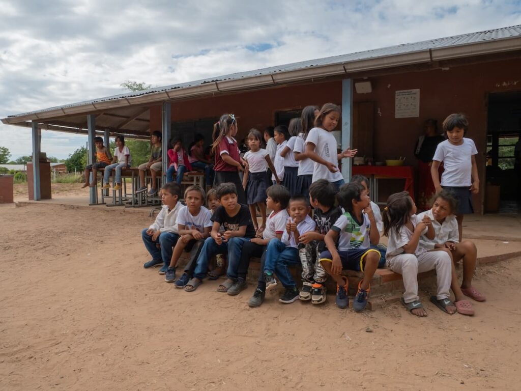 a group of kids sitting and standing outdoors