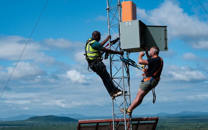 Dos hombres subiendo a una torre en una colina sobre un pueblo