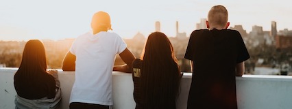 four person turned back looking at a city